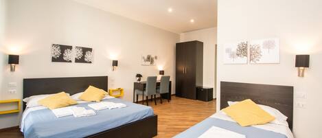 Habitación de hotel con dos camas, un escritorio y un armario.