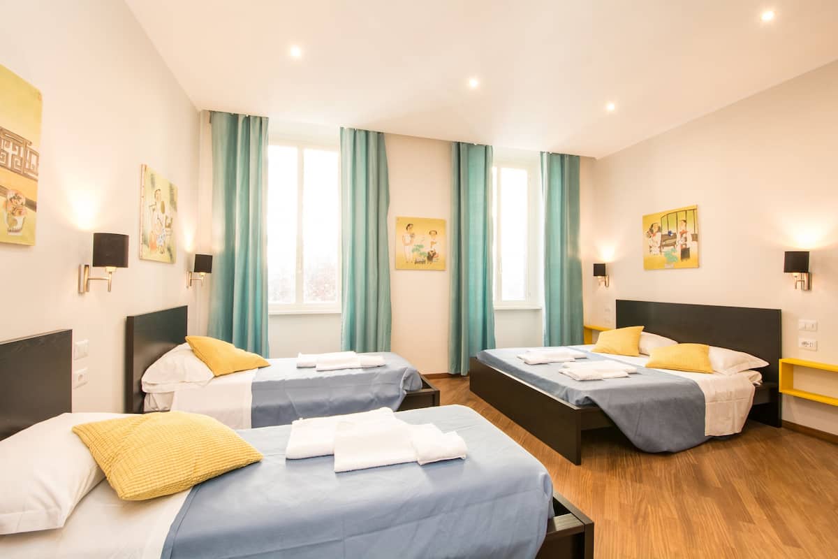 Ein Hotelzimmer mit zwei Betten, türkisfarbenen Vorhängen und Bildern an den Wänden.