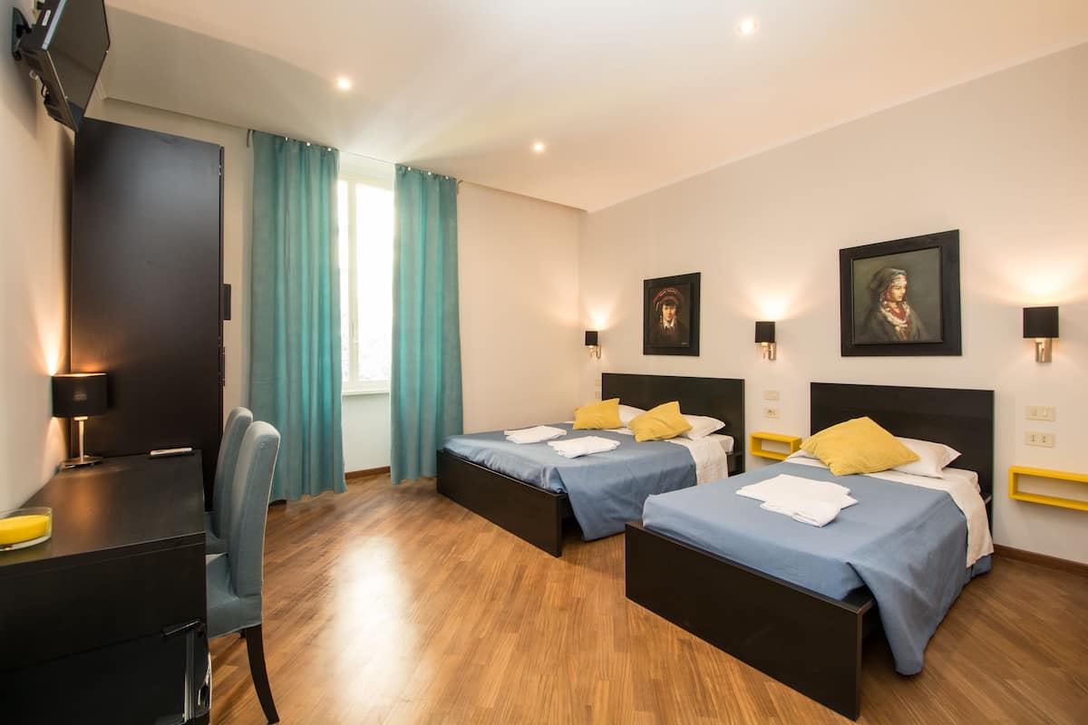 Ein Hotelzimmer mit zwei Betten, einem Schreibtisch und einem Stuhl.