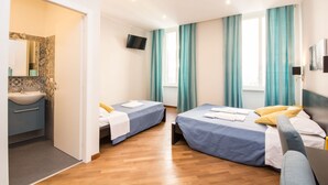 Een hotelkamer met twee bedden, een badkamer, een televisie en grote ramen voorzien van gordijnen.