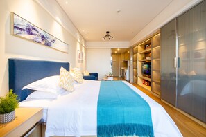 Une chambre à coucher moderne avec un grand lit, une tête de lit bleue, un plaid turquoise et une armoire avec un miroir.