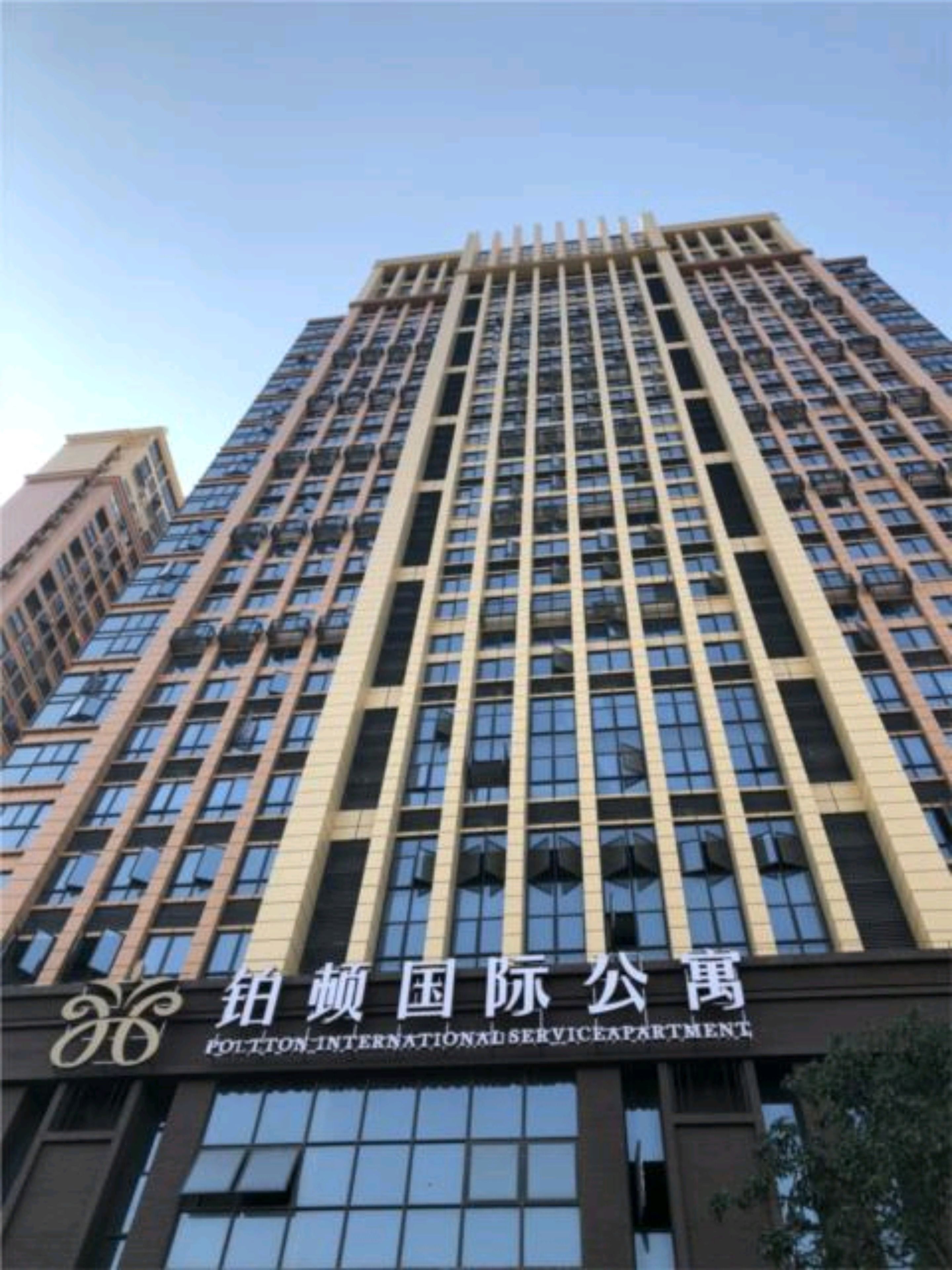 A tall building with a grid of windows and a sign that reads "POLITON INTERNATIONAL SERVICE APARTMENT".
