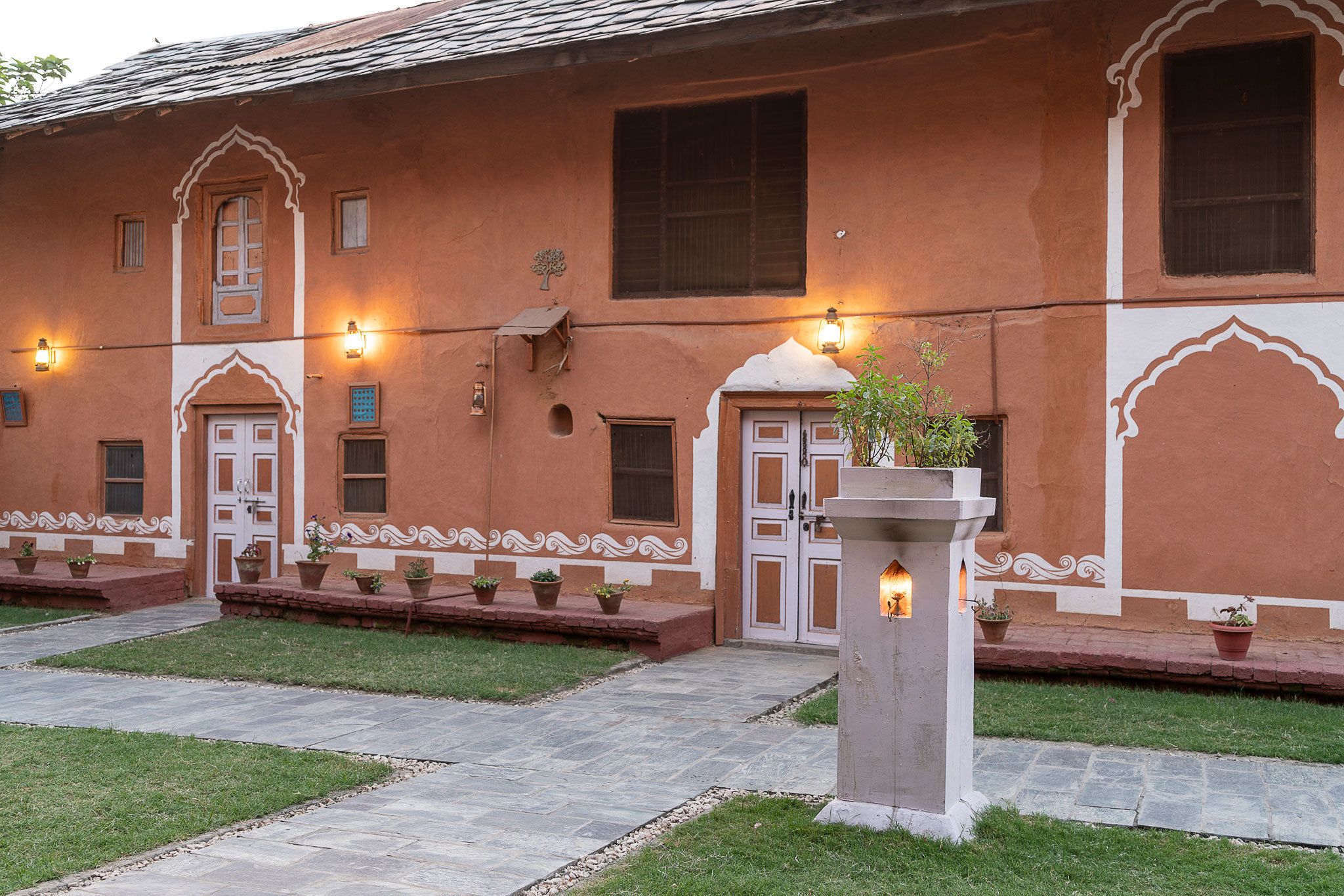 A traditional building with multiple doors and windows, potted plants, and a pathway.