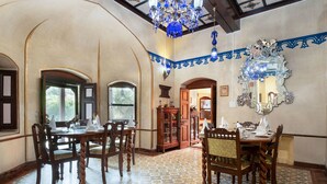 Un comedor con mesas y sillas de madera, un candelabro y un espejo grande en la pared.