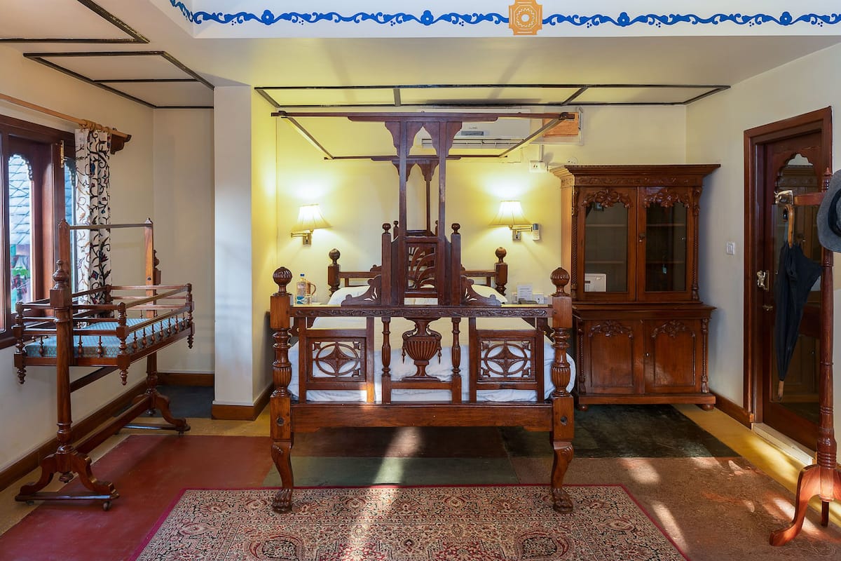A traditional wooden bed with a canopy, a wooden side table, and a mirror on the wall.