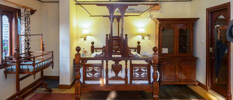 A traditional wooden bed with a canopy, a wooden side table, and a mirror on the wall.