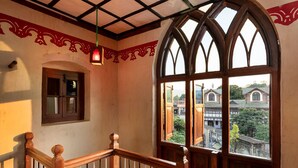Una escalera con barandillas de madera y un amplio ventanal de arco que ofrece vistas a edificios.