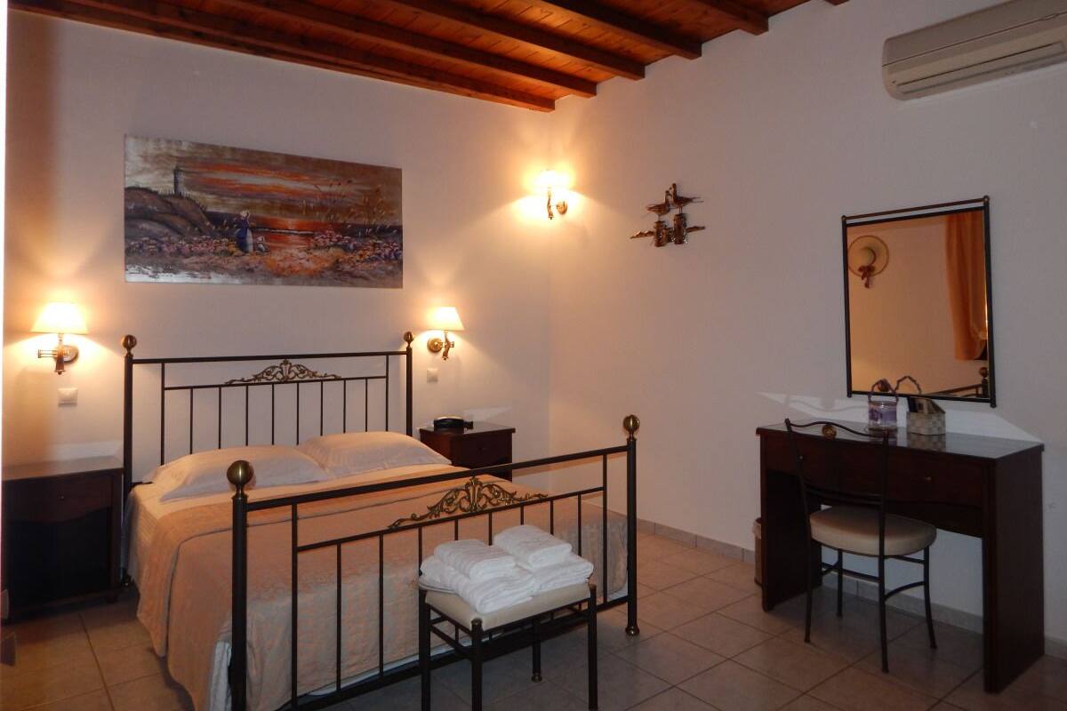 Une chambre à coucher comprenant un lit, des tables de chevet, un bureau, une chaise, un miroir et un tableau accroché au mur.