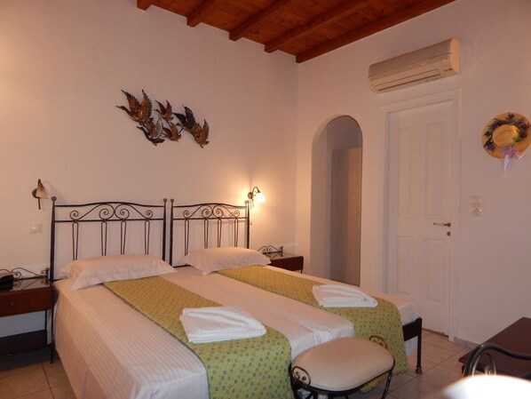 A double bed with a headboard, two bedside tables, a bench, and a door with an archway.