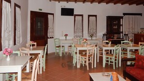 Un comedor con mesas y sillas de madera, un sofá rojo y techo de madera.