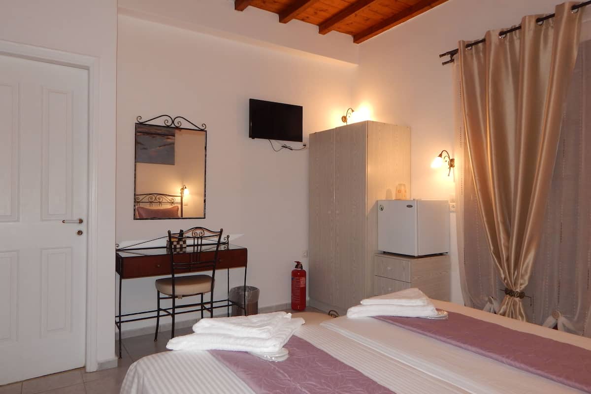 Une chambre à coucher comprenant un lit, un bureau avec une chaise, une armoire, un téléviseur et une salle de bain.