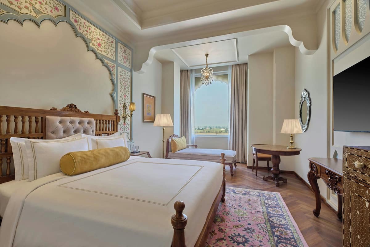 A hotel room with two beds, a chandelier, a TV, and a view of the outdoors.