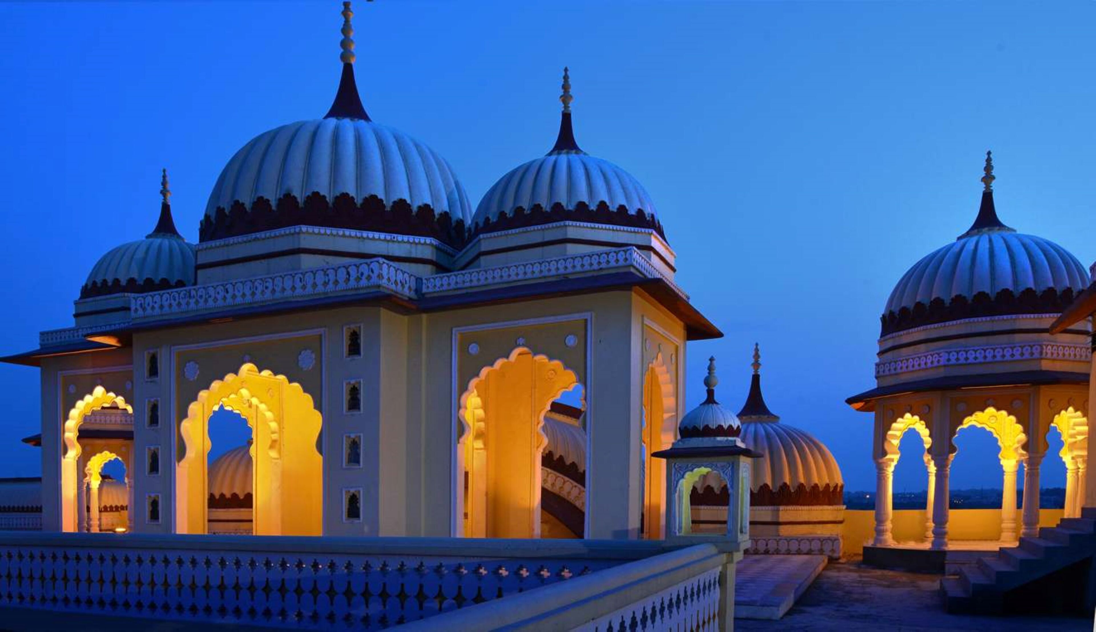 A traditional building with multiple domes and arched entrances, illuminated by warm lighting.