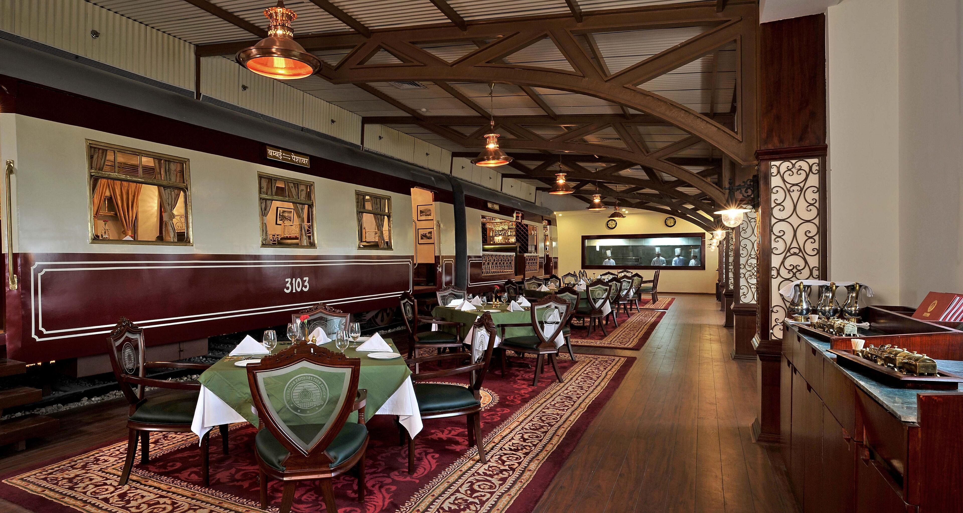 A restaurant with wooden booths numbered 3103, green upholstered chairs, and a long counter with a display.