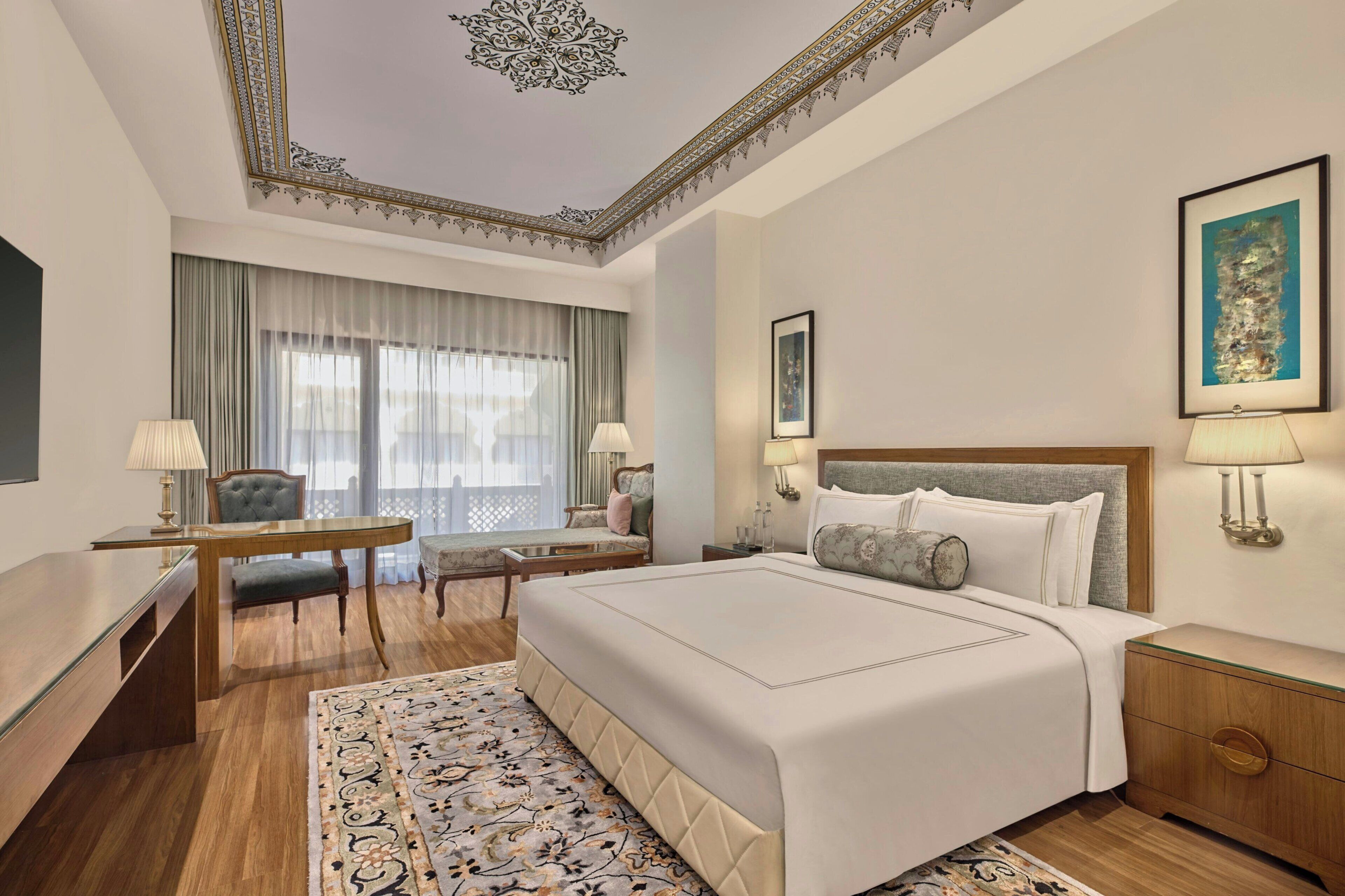 Una habitación de hotel con una cama grande, un escritorio, una silla, una mesa y un televisor.