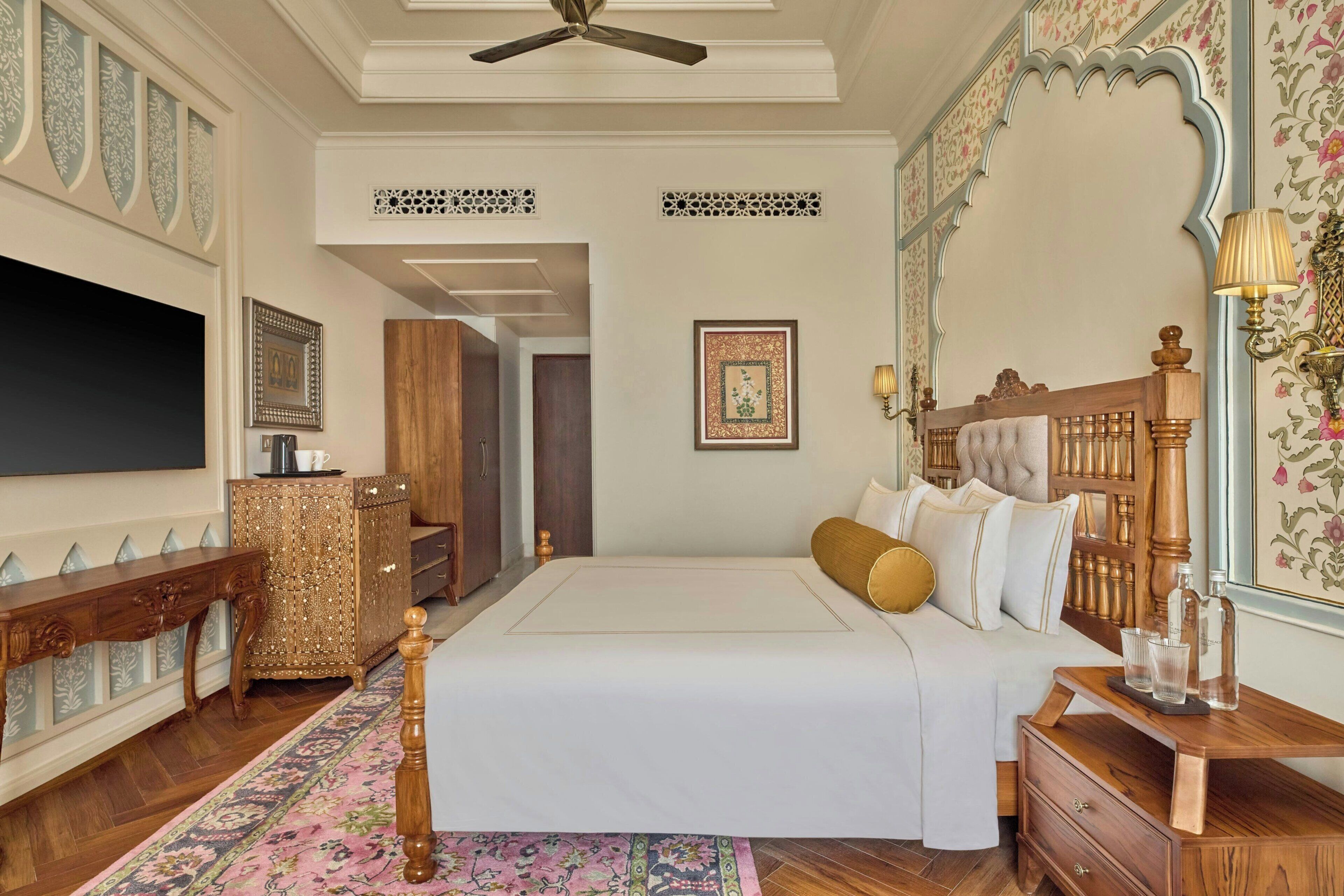 A bedroom with a bed, bedside tables, a wardrobe, a mirror, and a ceiling fan.