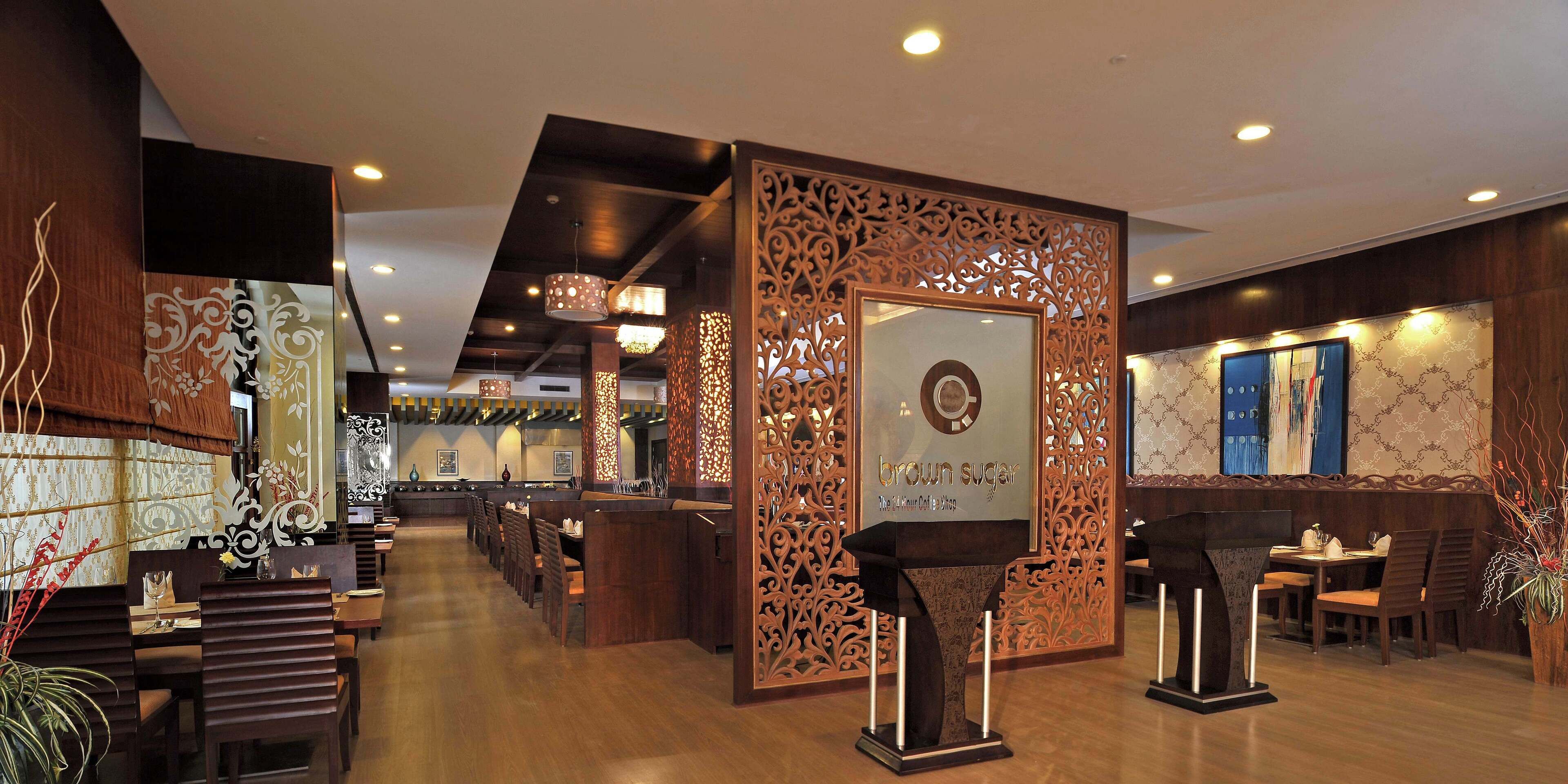Interior de restaurante moderno con mobiliario de madera, paneles decorativos y un letrero central que dice 'azúcar moreno'.