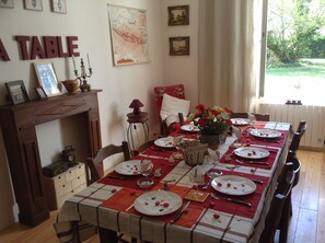 Een eetkamer met een lange tafel gedekt voor een maaltijd, een open haard en een kaart aan de muur.