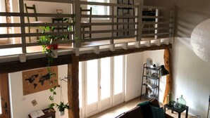 A loft-style room with a wooden floor, a loft bed, a desk, and a bookshelf. - Les chambres de Filou (Montesquieu)