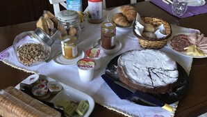 A dining table with various food items, including bread, pastries, and a cake, along with condiments and beverages. - La Ghirlanda B&B (Arezzo)
