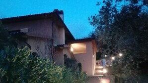 A stone pathway leading to a house with a porch, surrounded by greenery and potted plants. - La Ghirlanda B&B (Arezzo)