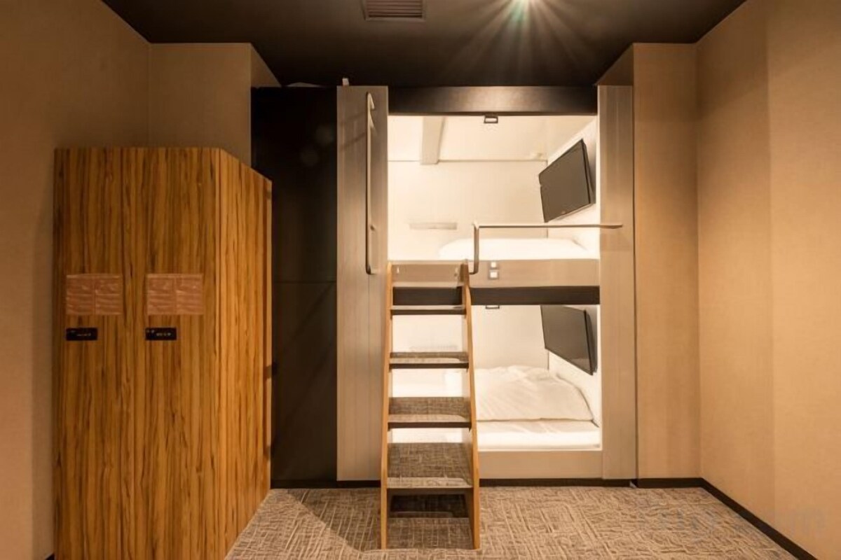 A room with a bunk bed, a wooden wardrobe, and a ladder leading to the upper bunk.