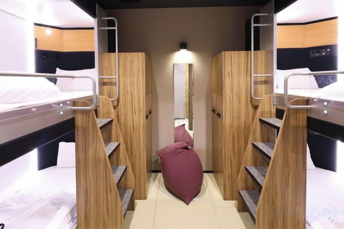 A bunk bed room with a central staircase, a mirror, and a light fixture.
