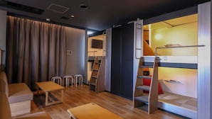Une chambre d’hôtel de taille réduite, équipée d’un lit superposé, d’un bureau et d’une chaise.