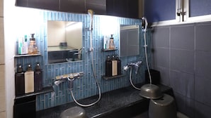 Une salle de bain avec deux lavabos, un miroir et une douche. On y trouve des articles de toilette sur le comptoir.