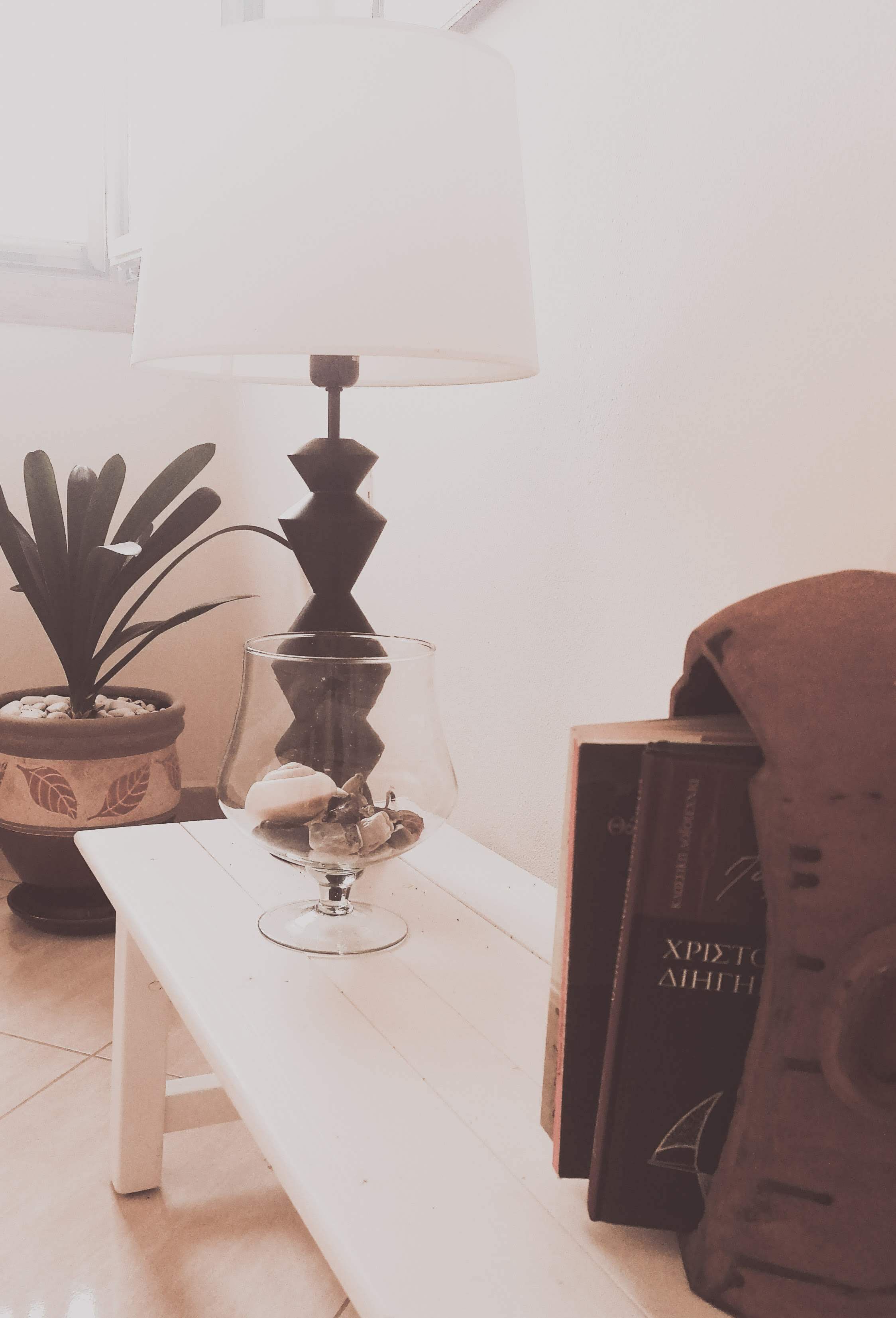 Un banc blanc, avec un vase en verre et une plante en pot à côté.