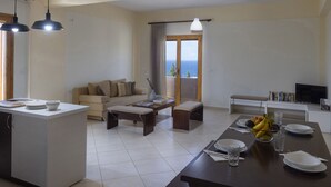 Un salon moderne comprenant un canapé, une table basse, une table à manger pour quatre personnes et un balcon avec vue.