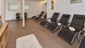 A room with four reclining chairs, a wooden bench, a white rug, and a wall-mounted artwork. - Gästehaus Bergkristall (Soelden)