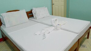 A double bed with white linens, two pillows, and a towel arranged in a heart shape on the bed. - Amos Digue Pension House (Puerto Princesa)