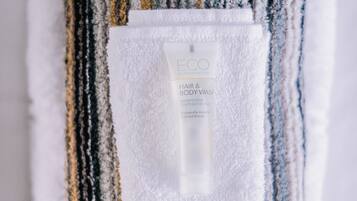 Una toalla doblada con un botellín de lavado ECO para cabello y cuerpo.