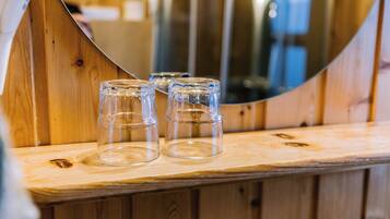 Tres vasos de vidrio transparentes sobre una superficie de madera, con un espejo curvo al fondo.