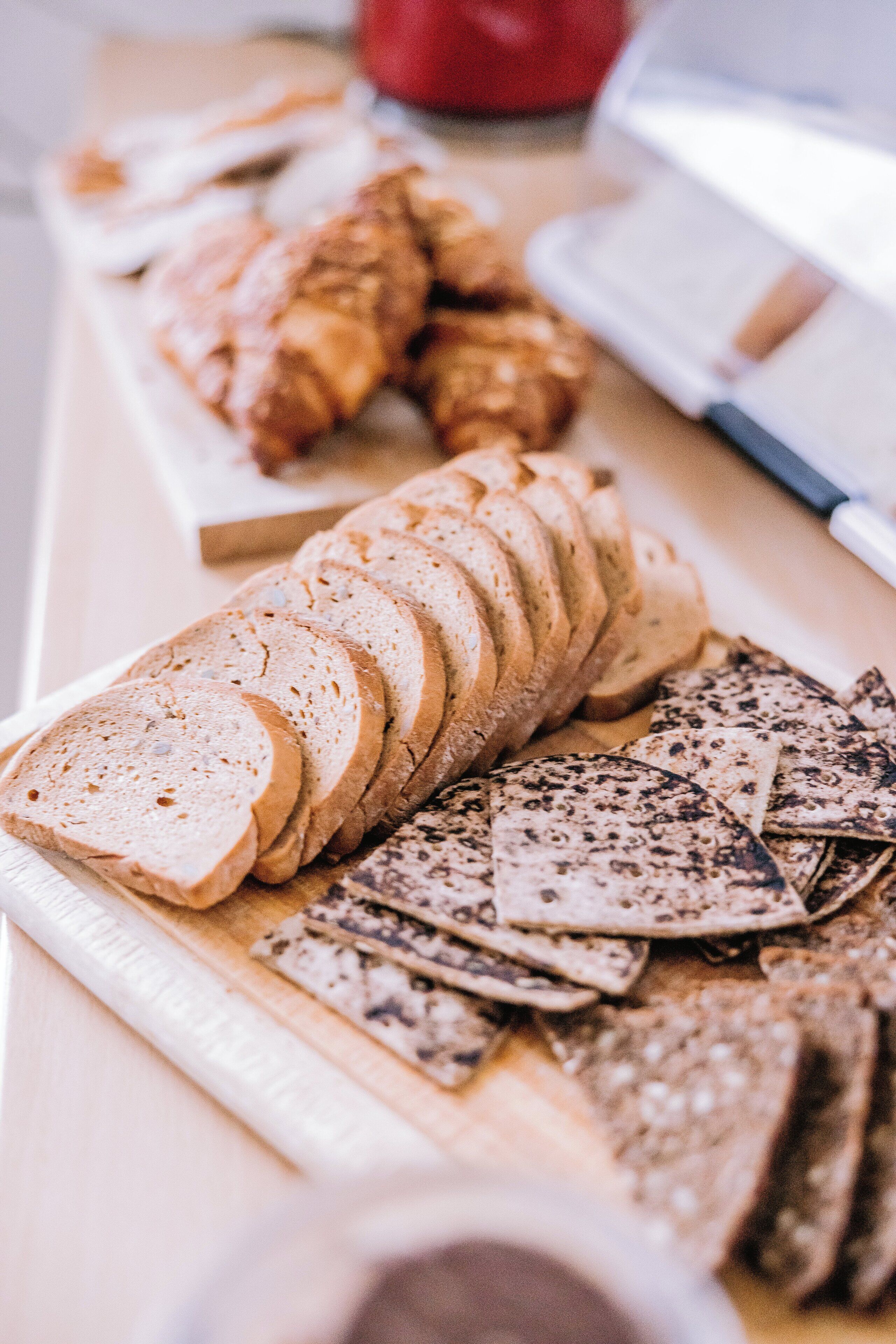 A variety of sliced bread and crackers on a wooden board.