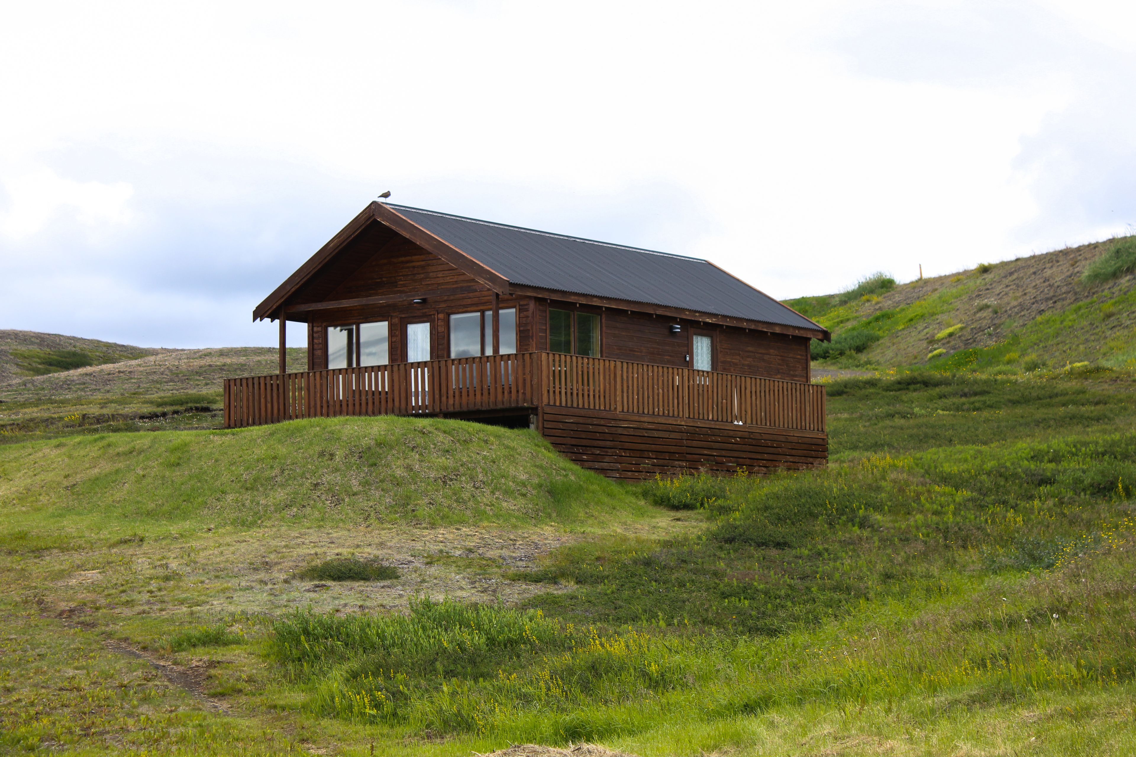 A wooden cabin with a sloped roof, large windows, and a balcony.
