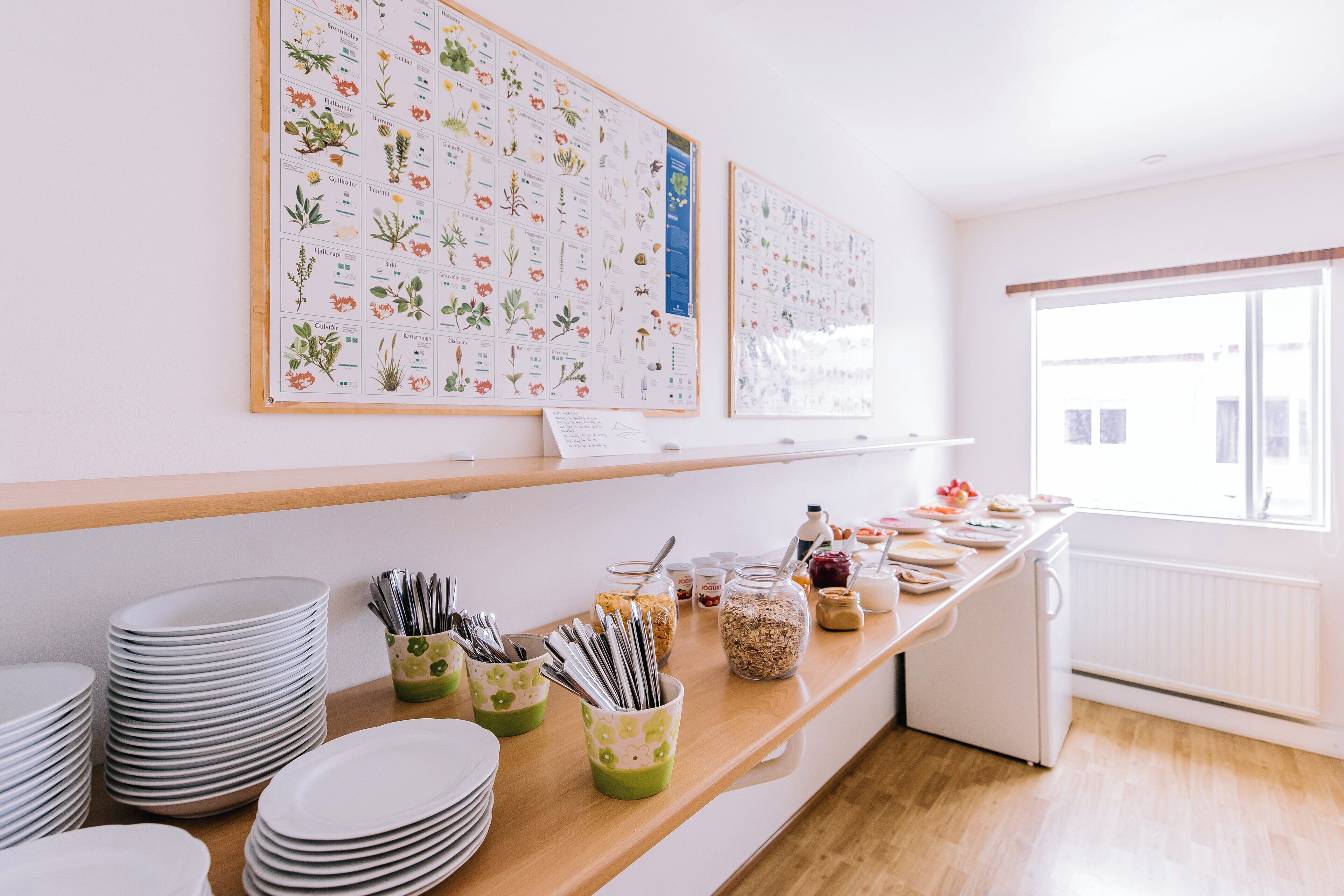 Un bufé de desayuno con platos, utensilios y recipientes para alimentos sobre una encimera de madera.