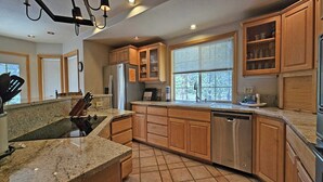 A modern kitchen with granite countertops, wooden cabinets, a dishwasher, and a large window providing natural light. - 6 Mt. Hood-Sunriver, Oregon: Hot Tub, BBQ, WiFi, SHARC Aquatics, Tubing Hill, Mt. Bachelor, Golf, Deschutes River, Tennis, Bike Paths (Sunriver)
