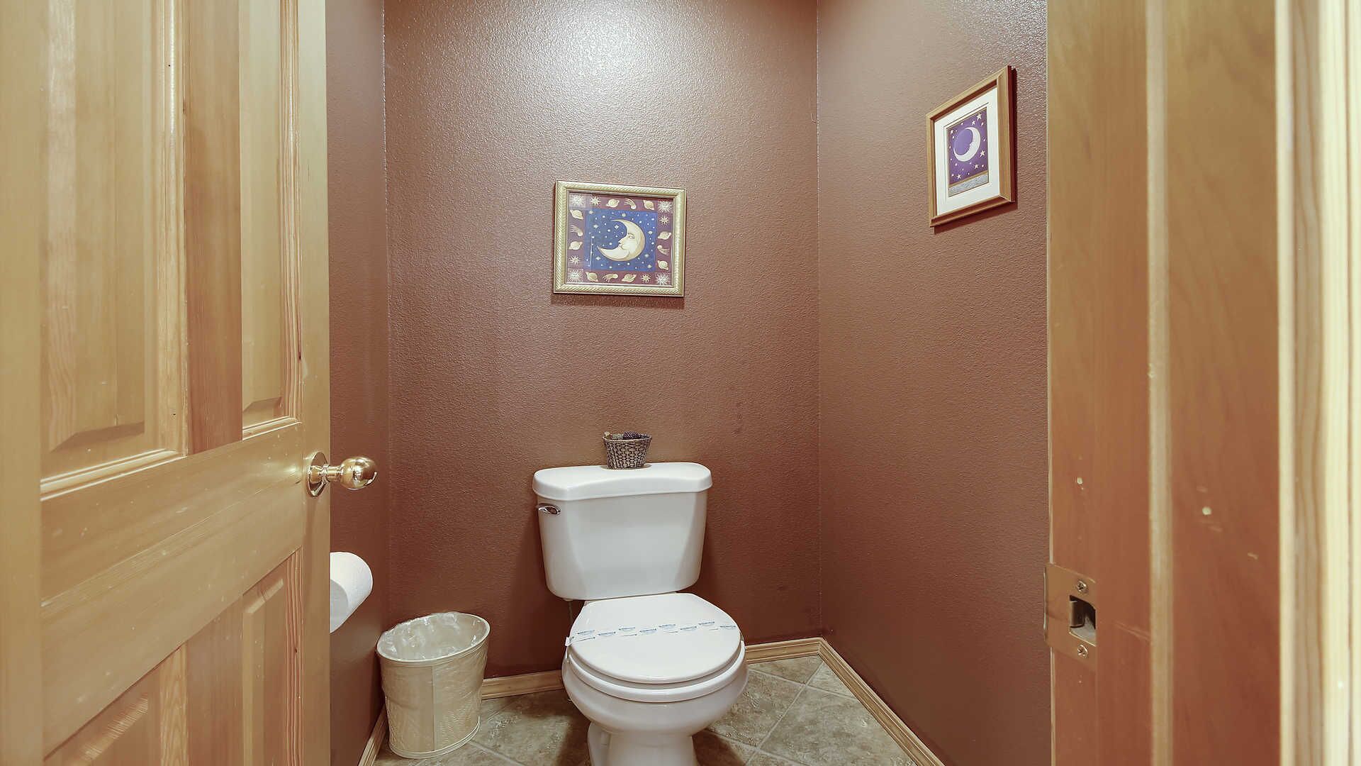 Ein kleines Badezimmer mit Toilette, einem Mülleimer und zwei gerahmten Bildern an der Wand.