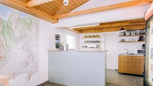A reception area with a wooden ceiling, a map on the wall, a counter with a plant, and shelves with helmets and equipment. - Hlíd Hostel (Myvatn)
