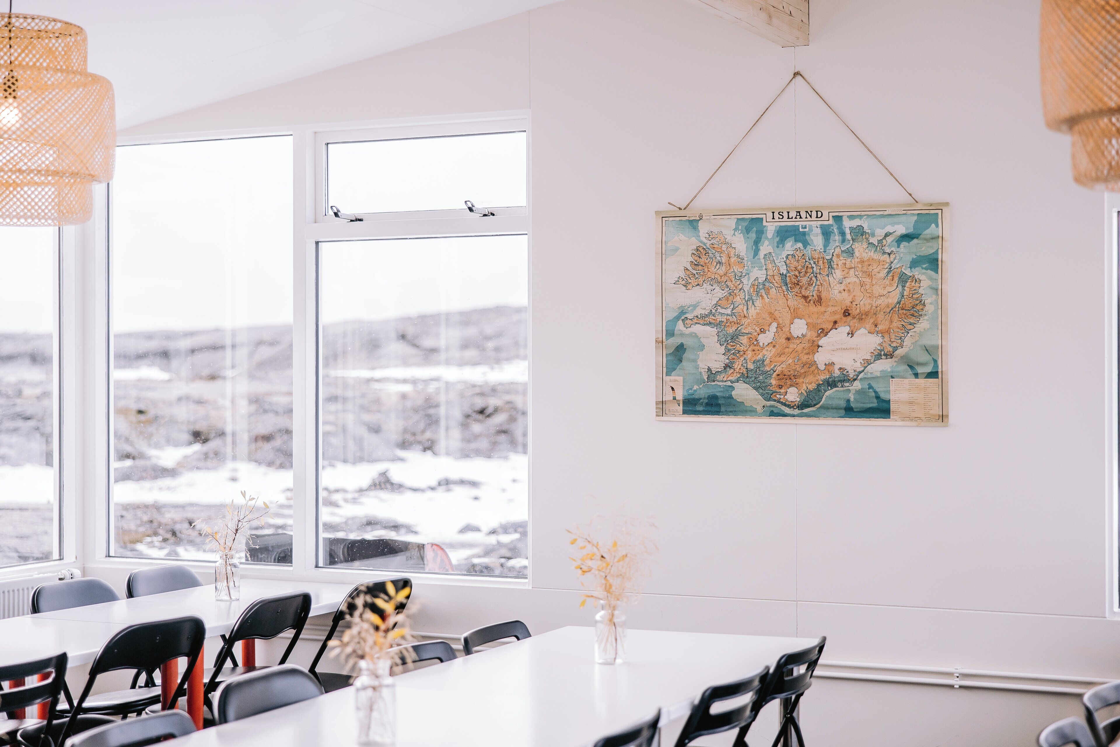 A conference room with a large window, a map on the wall, and a table with chairs.