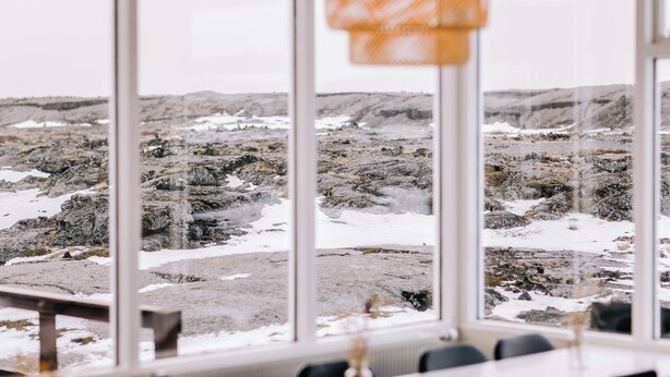 A room with large windows offering a view of a rocky landscape with snow patches. - Hlíd Hostel (Myvatn)