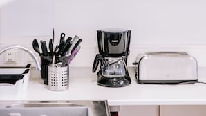 A kitchen with white cabinets, a coffee maker, a toaster, and a utensil holder. - Hlíd Hostel (Myvatn)