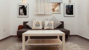 A living room with a sofa, two owl-themed cushions, a coffee table, and two wall-mounted light fixtures. - 2Rooms Perfect Location  1Min to  Beach (Tel Aviv)