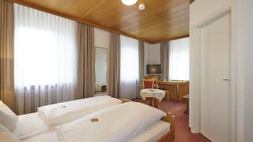 Habitación de hotel con dos camas, un escritorio, un televisor y un espejo.