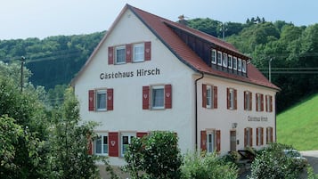 Un edificio de dos pisos con el nombre 'Gästehaus Hirsch' en la fachada.