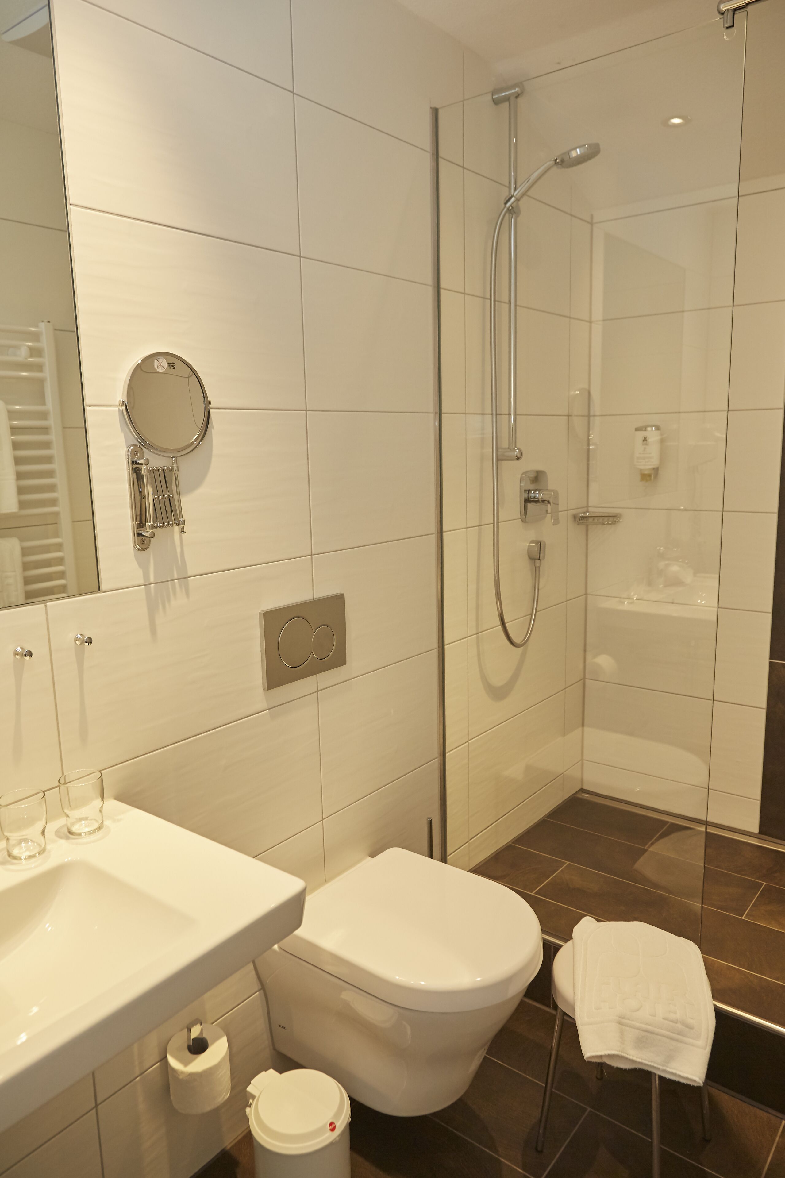 Ein modernes Badezimmer mit einer Duschkabine, einem weißen Waschbecken und einer Toilette.