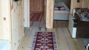 Une cabane en bois avec un lit, un canapé et un téléviseur fixé au mur.