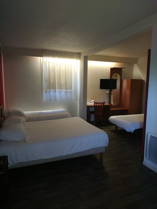 Habitación de hotel con dos camas, un escritorio, una silla, un televisor y un reloj en la pared.